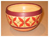 A Bali stoneware bowl, decorated with geometric design with 4 leaves on peach colour background - third view.