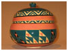 A Bali stoneware pot with lid, decorated with geometric design in triangle shapes using blue-green and salmon colour glazes - second view.
