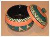 A Bali stoneware pot with lid, decorated with geometric design in triangle shapes using blue-green and salmon colour glazes - first view.