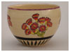 A Bali stoneware pot decorated with primula flowers on cream background - first view.